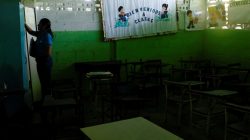 A teacher stands next to a billboard that reads "Welcome to classes" and empty desks in a classroom on the first day of school, in Caucagua, Venezuela September 17, 2018. REUTERS/Marco Bello