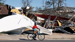 A man carries food and water past a building damaged by Hurricane Michael in Parker, Florida, U.S., October 13, 2018. REUTERS/Terray Sylvester