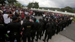 Guatemalan police officers watch as Honduran migrants, part of a caravan trying to reach the U.S., arrive in Esquipulas city in Guatemala, October 15, 2018. REUTERS/Jorge Cabrera