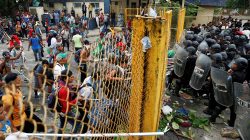 Men, part of a caravan of thousands of migrants from Central America en route to the U.S., push the border gate as they try to cross into Mexico and carry on their journey, in Tecun Uman, Guatemala, October 28, 2018. REUTERS/Carlos Garcia Rawlins
