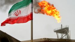 FILE PHOTO: A gas flare on an oil production platform in the Soroush oil fields is seen alongside an Iranian flag in the Persian Gulf, Iran, July 25, 2005. To match Exclusive OPEC-OIL/ REUTERS/Raheb Homavandi/File Photo/File Photo